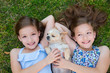 twin sisters playing with chihuahua dog lying on lawn